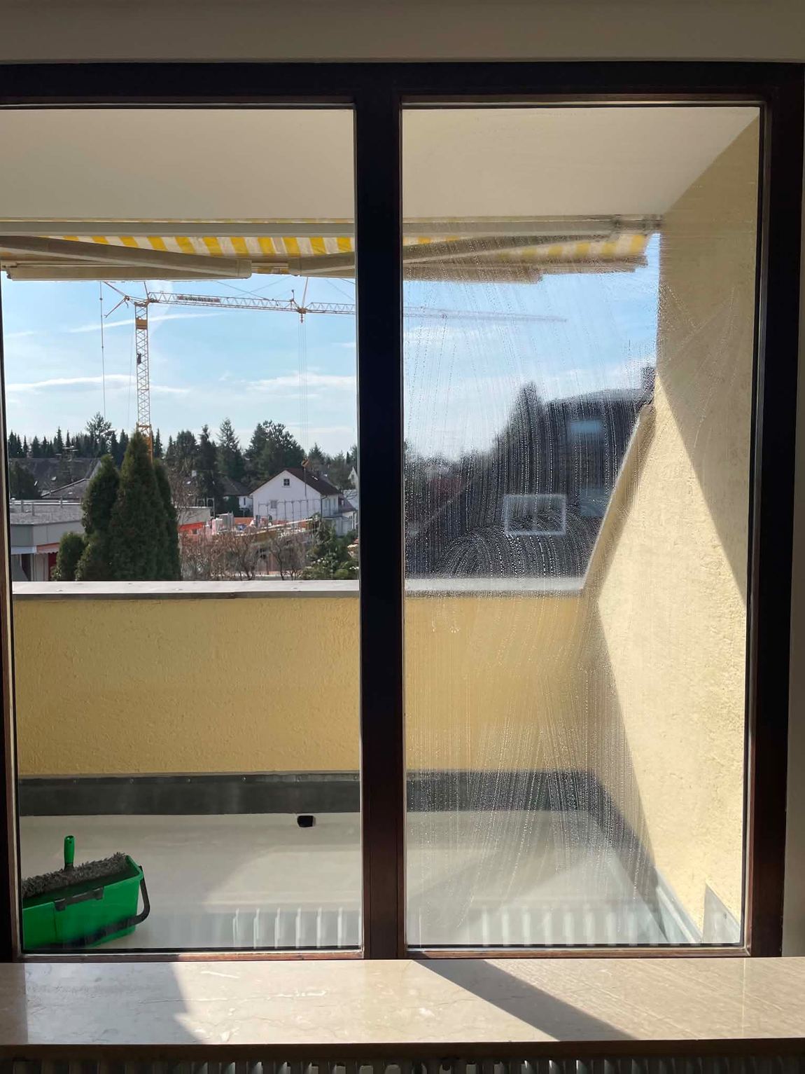 Große Fensterfront wird mit Einwascher und Abzieher gereinigt, eine Scheibe ist bereits fertig