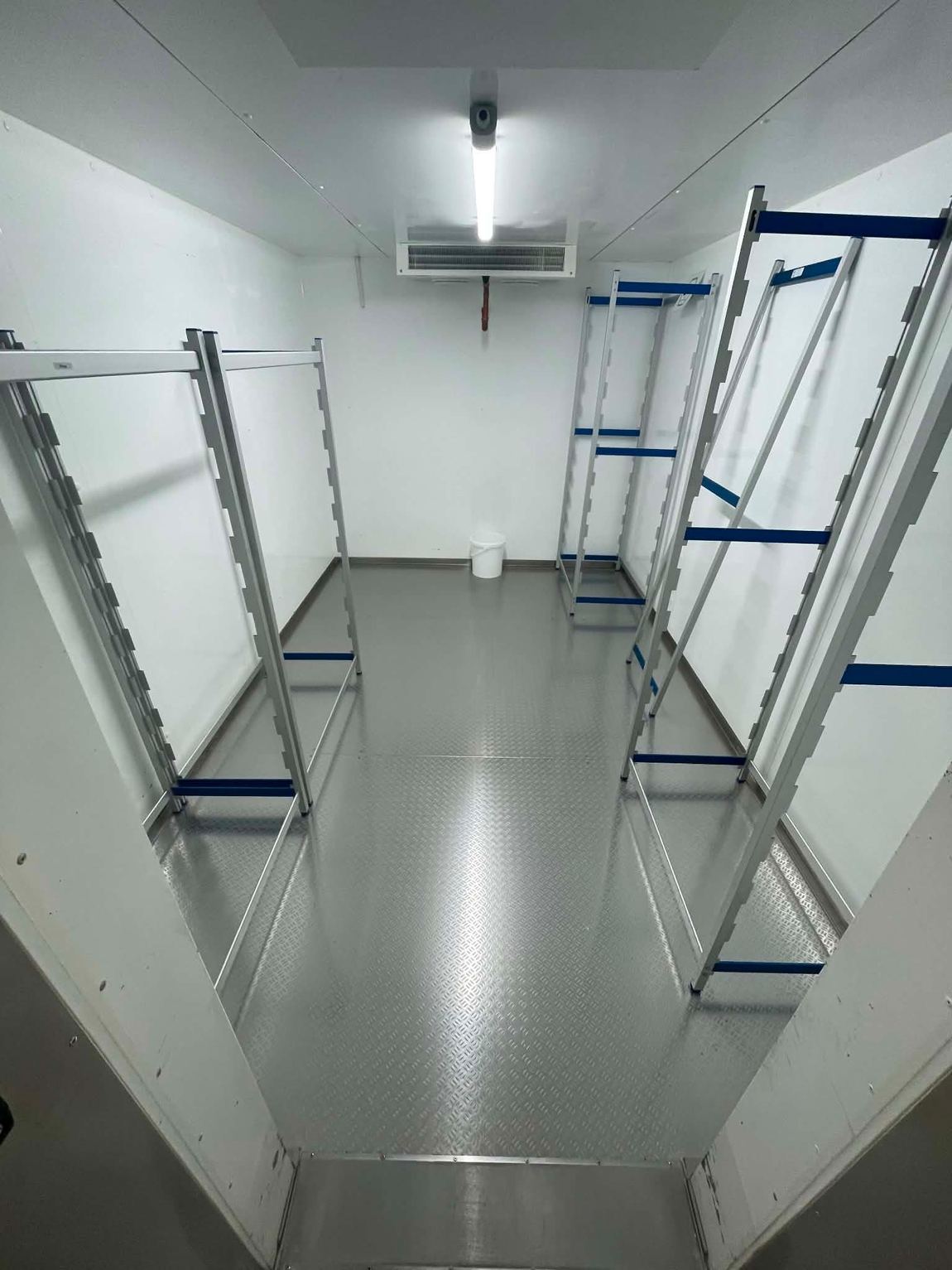 Gereinigter Kühlraum mit Edelstahlboden und leeren Regalsystemen